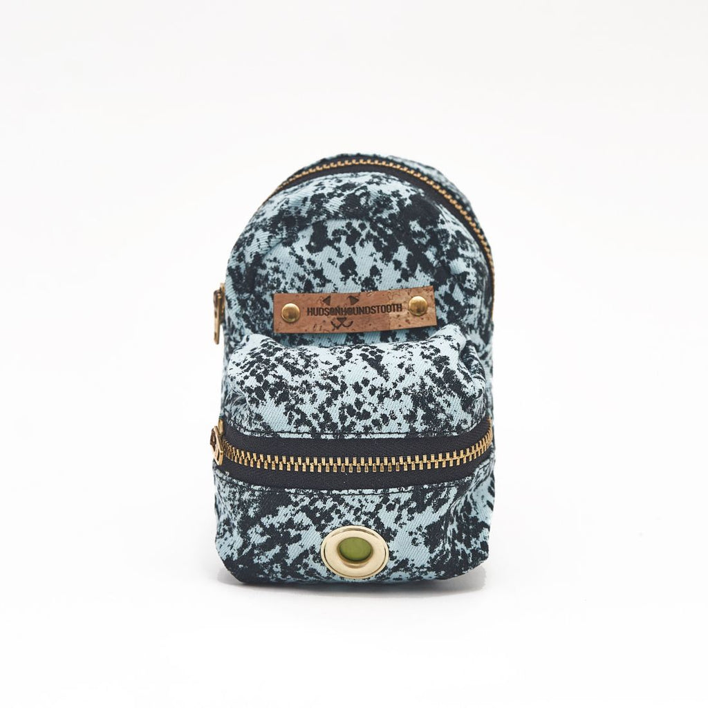 Pale aqua Twill with Black snake print dog mini backpack waste bag and treat dispenser. Features black YKK zippers, brass hardware and cork Hudson Houndstooth label.