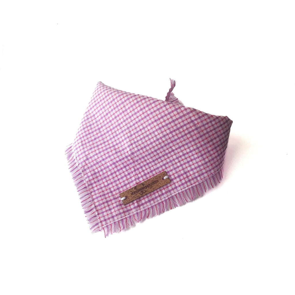Image shows Hudson Houndstooth Berry Sorbet Seersucker plaid dog bandana tied with delicate hand frayed edge and vegan cork leather label. Plaid features bright pink and purple colors perfect for summer.
